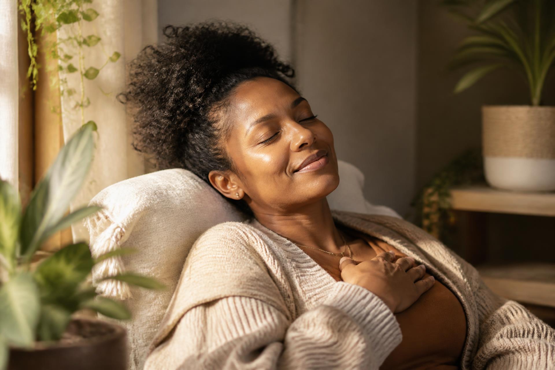 An African American woman resting peacefully in soft morning light surrounded by plants